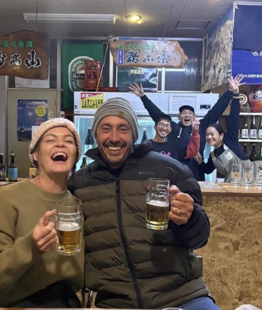 Guests raising beer glasses with smiling people behind them